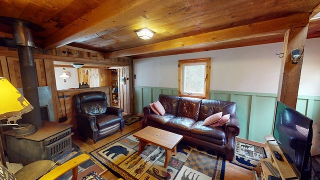 living room with a wood stove, wooden walls, light hardwood / wood-style floors, beam ceiling, and wood ceiling