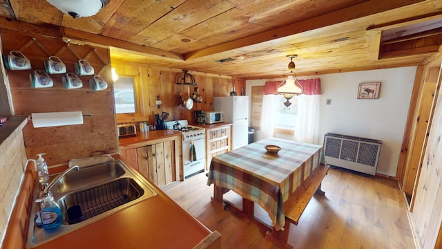 kitchen featuring radiator, white appliances, sink, decorative light fixtures, and light hardwood / wood-style floors