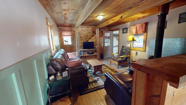 living room with wood ceiling, a wood stove, a wealth of natural light, and light hardwood / wood-style flooring