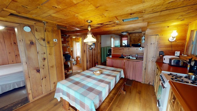 dining area with wood walls, wood ceiling, and light hardwood / wood-style flooring