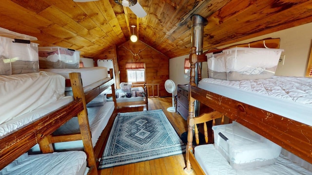 bedroom featuring wooden walls, vaulted ceiling, ceiling fan, wood-type flooring, and wood ceiling