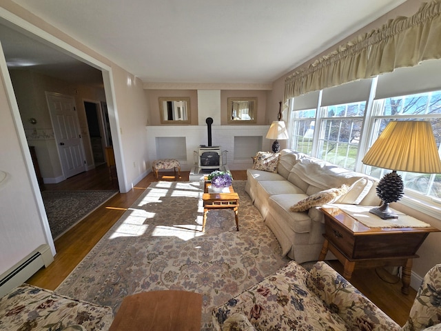 living room with a wood stove, a baseboard radiator, and hardwood / wood-style flooring