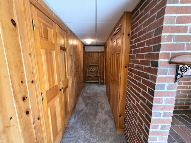 hallway with wood walls, a wall unit AC, brick wall, and dark carpet