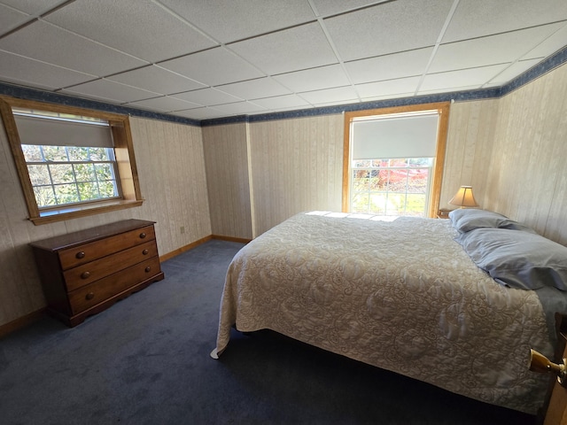 bedroom featuring a drop ceiling and dark carpet