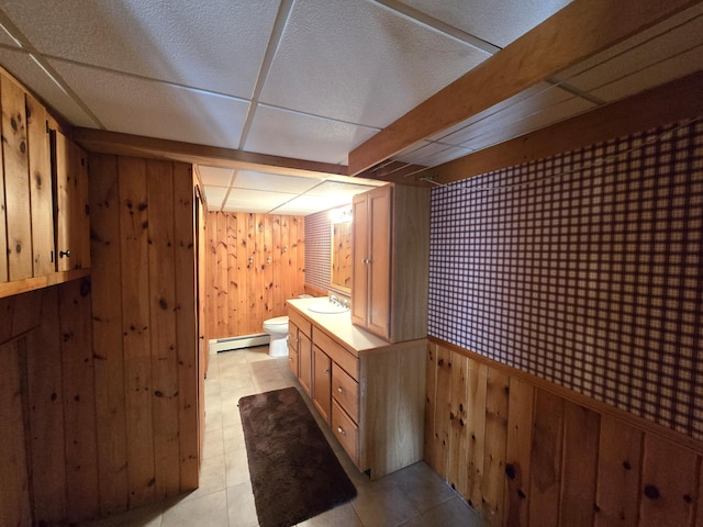 bathroom featuring toilet, wood walls, vanity, and a drop ceiling