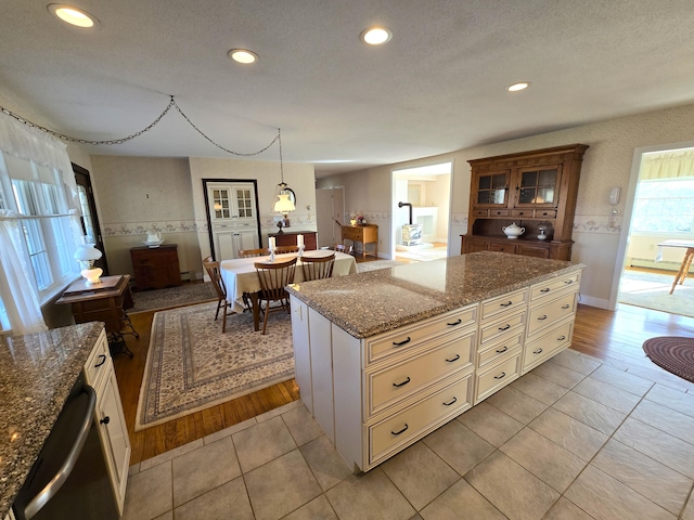 kitchen featuring stainless steel dishwasher, a textured ceiling, light wood-type flooring, and a kitchen island