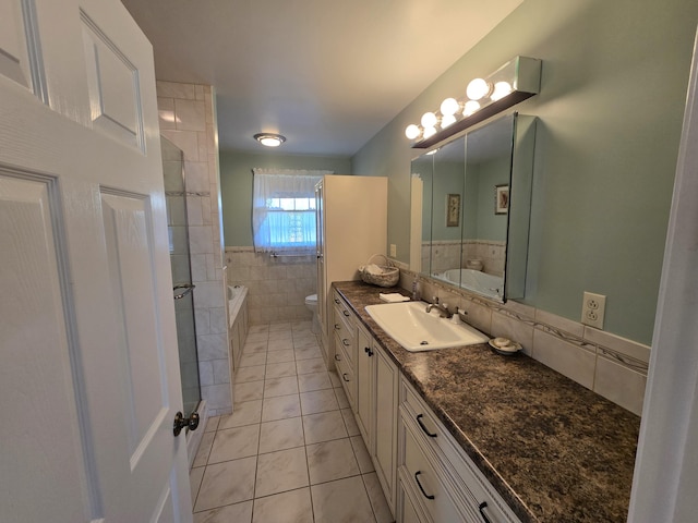 bathroom with toilet, tile walls, tile patterned flooring, vanity, and a tub to relax in