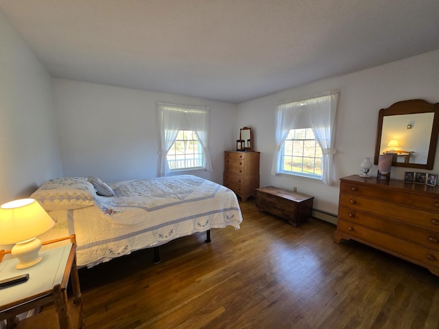 bedroom with a baseboard radiator, dark wood-type flooring, and multiple windows