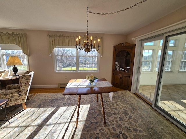 dining area with hardwood / wood-style flooring, baseboard heating, and an inviting chandelier