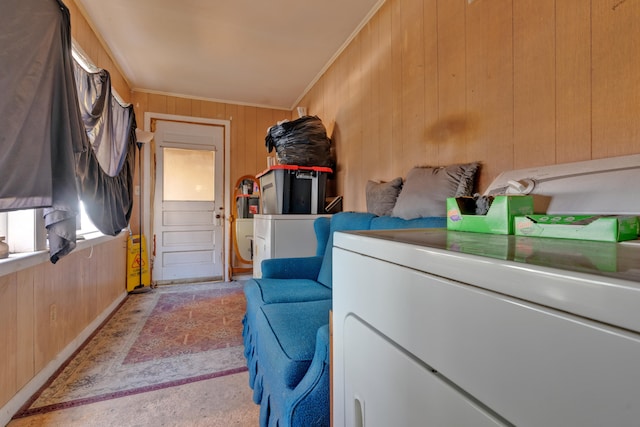 clothes washing area with wood walls, ornamental molding, and washer and clothes dryer
