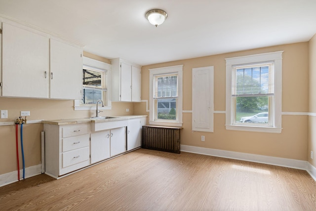 19 Harding St, Biddeford, ME 04005 - kitchen with a sink, radiator heating unit, light countertops, light wood-type flooring, and white cabinetry