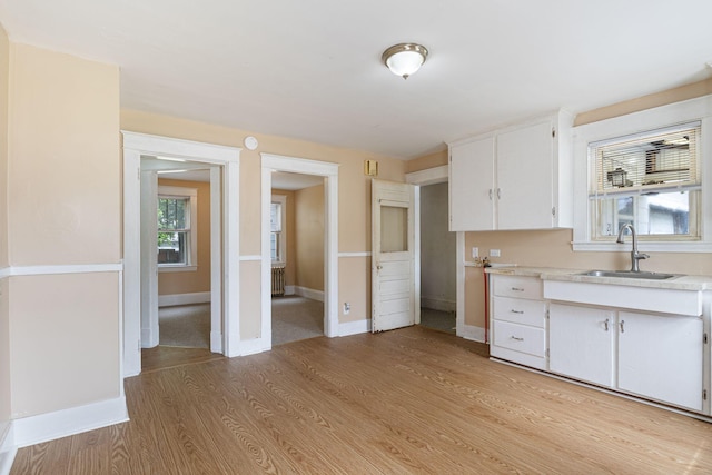 19 Harding St, Biddeford, ME 04005 - kitchen featuring a sink, light countertops, white cabinets, light wood-style floors, and baseboards