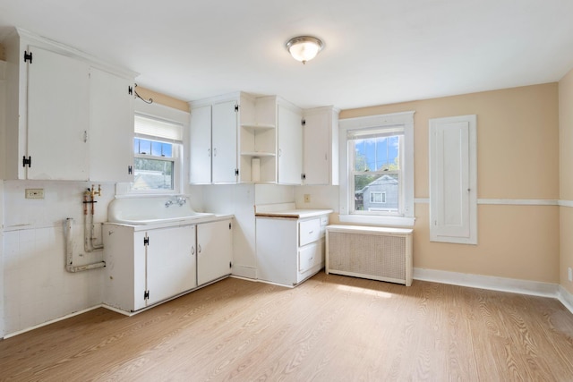 19 Harding St, Biddeford, ME 04005 - kitchen featuring radiator heating unit, a sink, light wood-style floors, open shelves, and white cabinets
