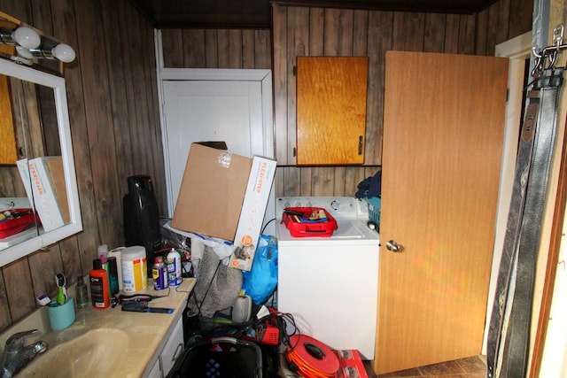 interior space featuring washer / dryer, sink, cabinets, and wooden walls