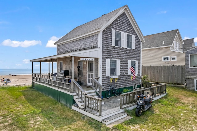 back of property with a water view and a lawn