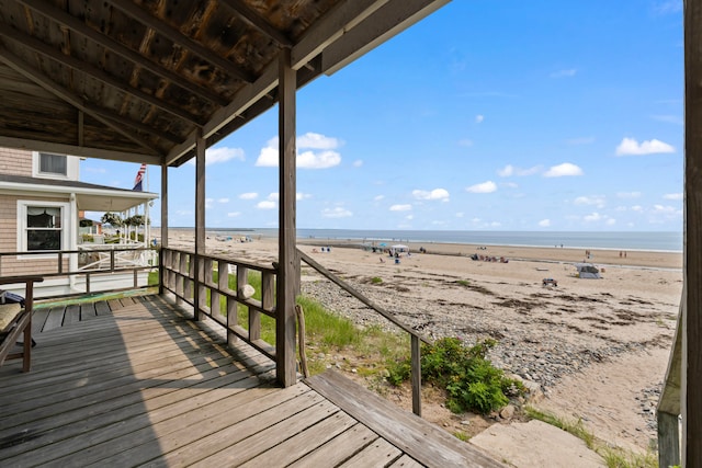 wooden terrace featuring a water view and a view of the beach