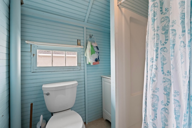 bathroom featuring toilet and wood walls