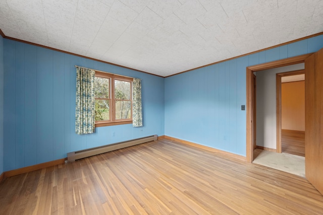 empty room with wood walls, light hardwood / wood-style floors, baseboard heating, and ornamental molding