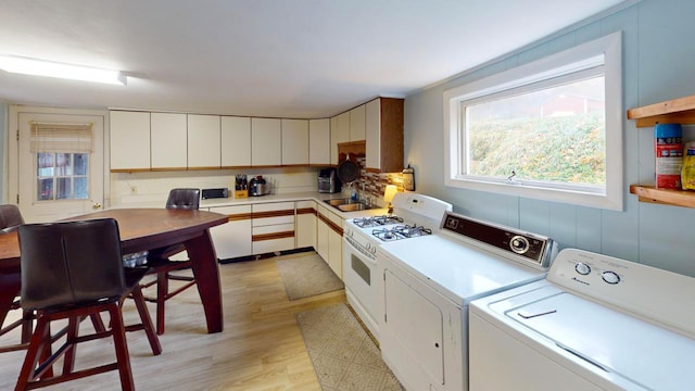 clothes washing area featuring separate washer and dryer, sink, and light wood-type flooring