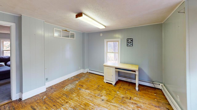 interior space with a textured ceiling, hardwood / wood-style flooring, baseboard heating, and a wealth of natural light