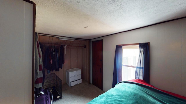 bedroom with wooden walls, light carpet, and a textured ceiling