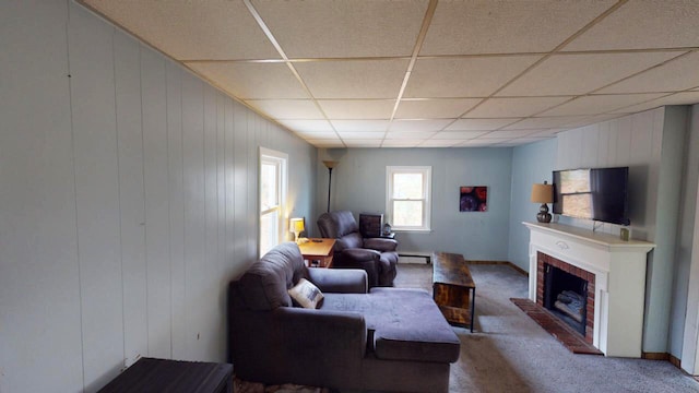 carpeted living room featuring a baseboard radiator, wooden walls, a fireplace, and a paneled ceiling