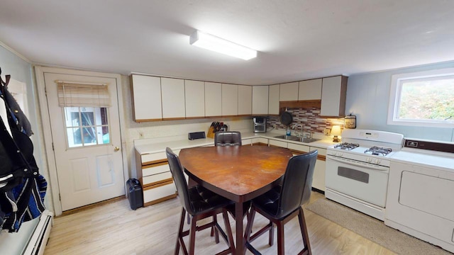 kitchen featuring white gas range, a baseboard heating unit, backsplash, sink, and light hardwood / wood-style floors