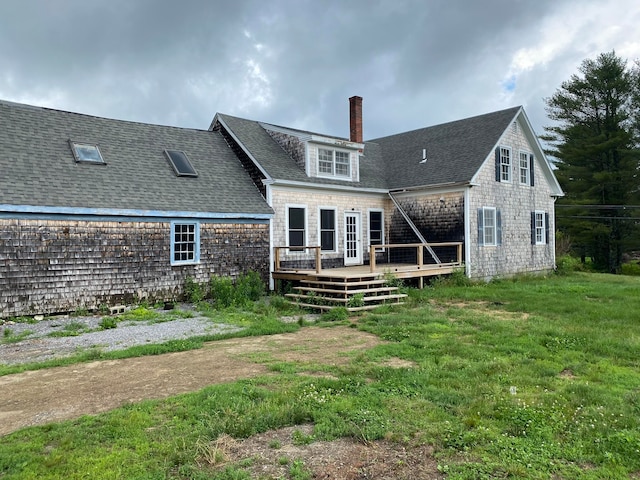 back of property with a wooden deck and a lawn