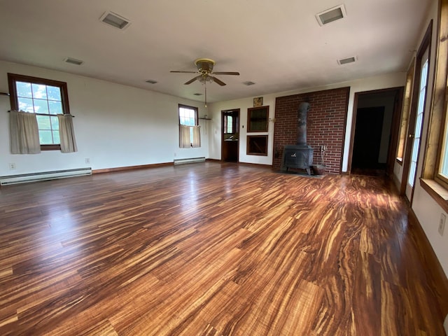 unfurnished living room with ceiling fan, a wood stove, dark hardwood / wood-style flooring, and baseboard heating