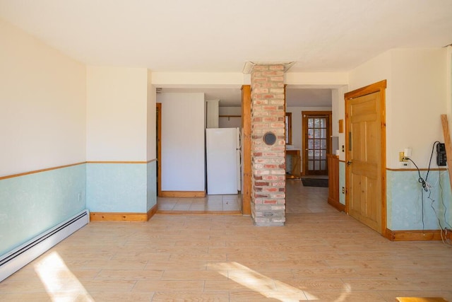 empty room with ornate columns, light hardwood / wood-style flooring, and a baseboard radiator