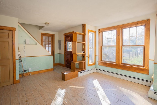 spare room with electric panel, light hardwood / wood-style floors, and a baseboard radiator