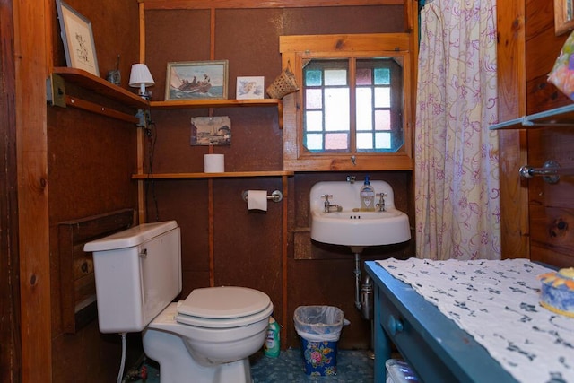 full bath with toilet, a shower with shower curtain, and a sink