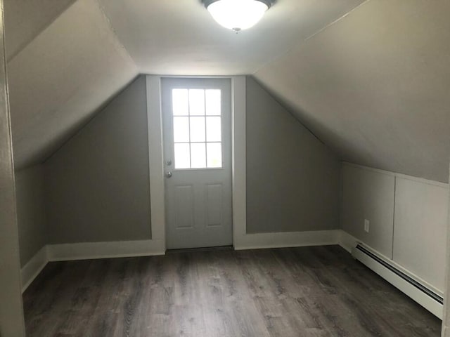 additional living space featuring baseboard heating, vaulted ceiling, and dark hardwood / wood-style flooring