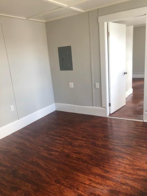 empty room featuring electric panel and dark hardwood / wood-style flooring