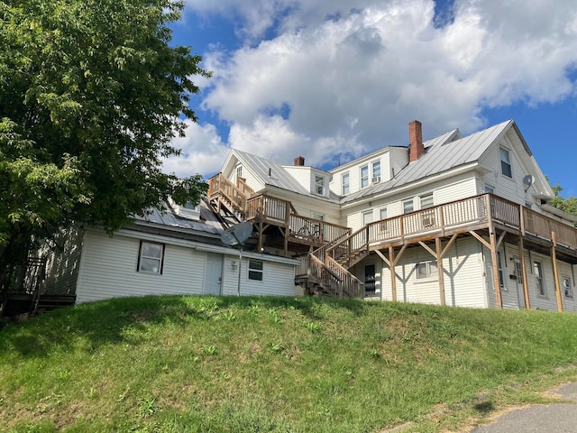 rear view of house with a wooden deck and a lawn