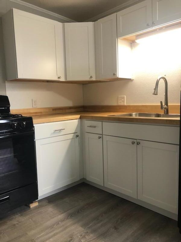 kitchen with black range oven, white cabinets, and dark wood-type flooring