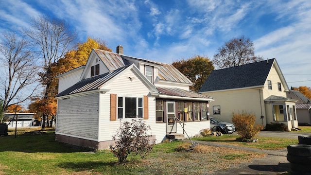 185 Knox St, Millinocket, ME 04462 - view of front of home with a chimney, a sunroom, metal roof, and a front yard