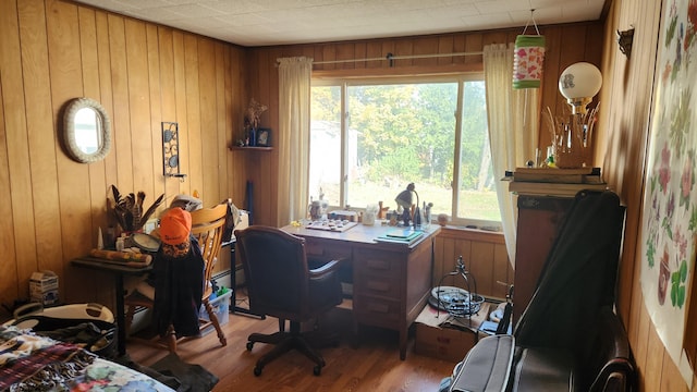 office space with baseboard heating, wood walls, wood-type flooring, and plenty of natural light