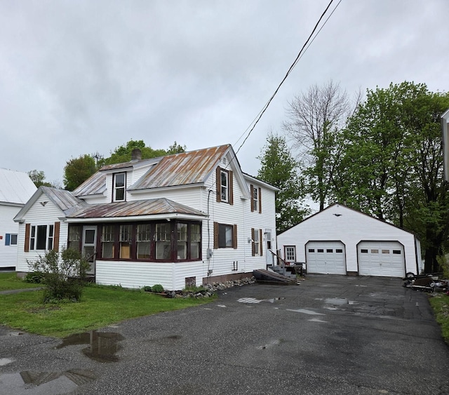 185 Knox St, Millinocket, ME 04462 - traditional-style house featuring a garage, a chimney, metal roof, an outbuilding, and a sunroom