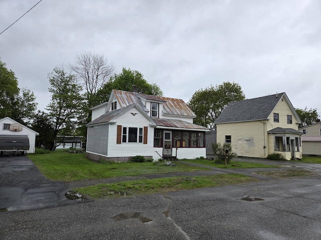 185 Knox St, Millinocket, ME 04462 - view of front of property featuring a sunroom, metal roof, a front lawn, and an outdoor structure