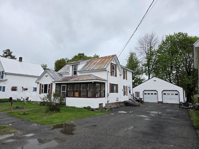 185 Knox St, Millinocket, ME 04462 - view of front of home featuring a detached garage, an outbuilding, a sunroom, metal roof, and a chimney