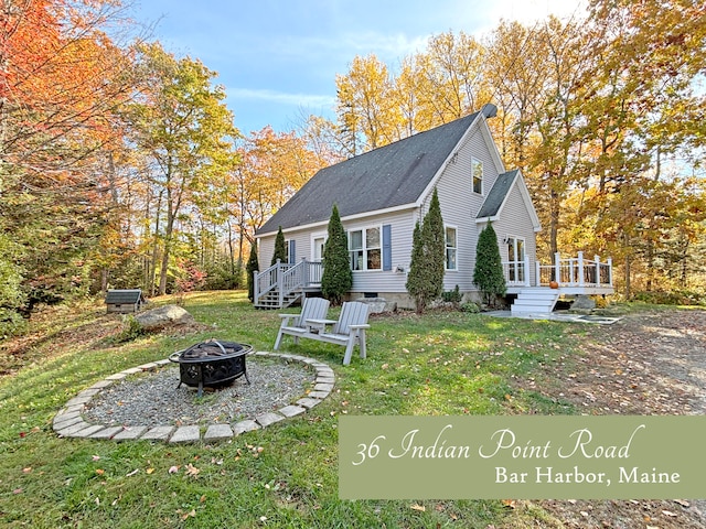 exterior space featuring a front lawn, a fire pit, and a deck