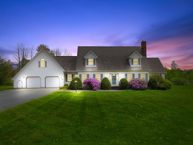 cape cod-style house featuring a yard and a garage