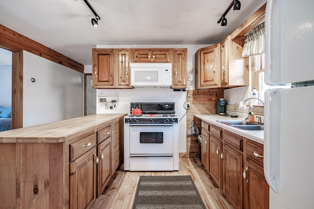 kitchen featuring sink, light hardwood / wood-style flooring, track lighting, and white appliances