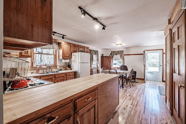 kitchen with white appliances, sink, light wood-type flooring, wood counters, and rail lighting