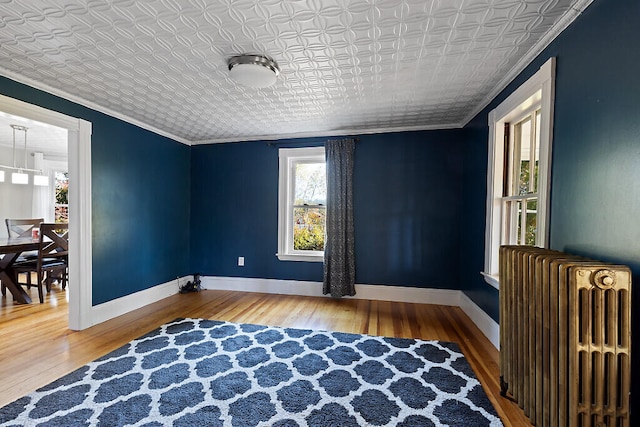 living area with wood-type flooring, radiator heating unit, and ornamental molding