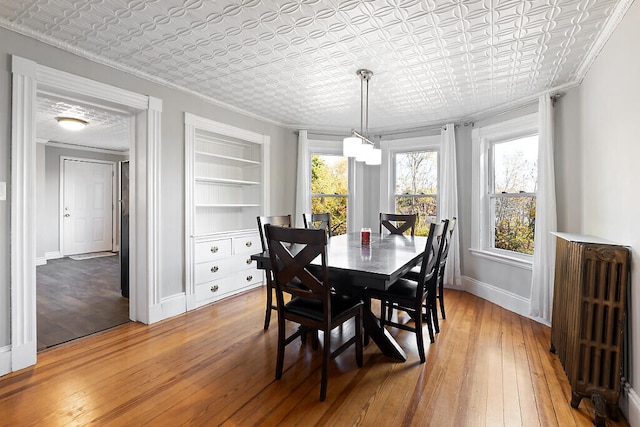 dining area with built in shelves, ornamental molding, radiator heating unit, and hardwood / wood-style floors