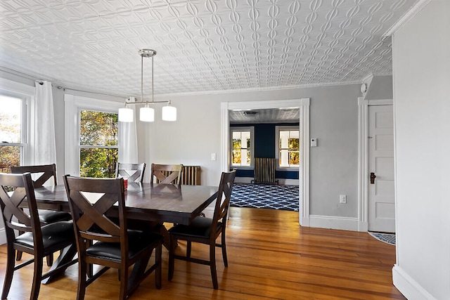 dining space featuring dark wood-type flooring, a healthy amount of sunlight, and ornamental molding