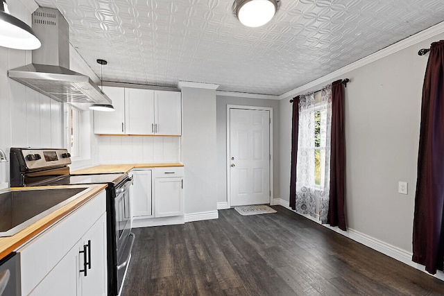 kitchen featuring wall chimney range hood, white cabinets, hanging light fixtures, appliances with stainless steel finishes, and dark wood-type flooring