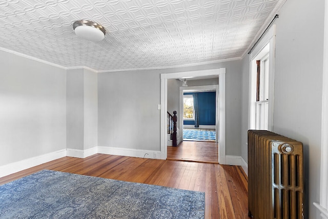 spare room featuring radiator, wood-type flooring, and ornamental molding